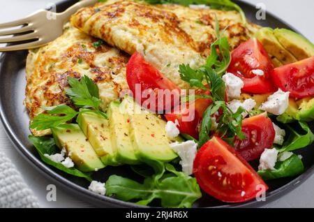 Omelette serviert mit Avocado und Kirschtomaten, gesundes Frühstück auf hellem Hintergrund Stockfoto