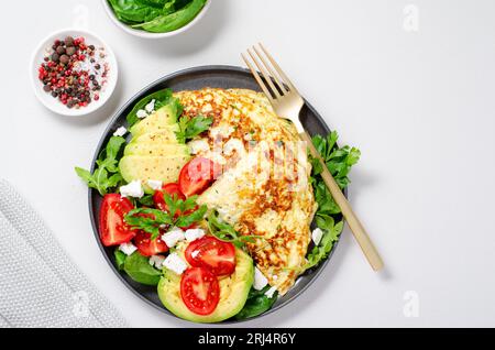 Omelette serviert mit Avocado und Kirschtomaten, gesundes Frühstück auf hellem Hintergrund Stockfoto