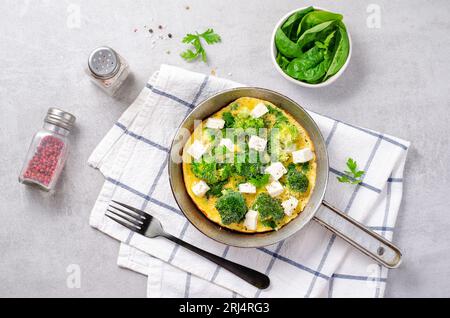 Omelette mit Brokkoli und Feta-Käse in einer Pfanne, gebackenes Omelett auf hellem Hintergrund Stockfoto
