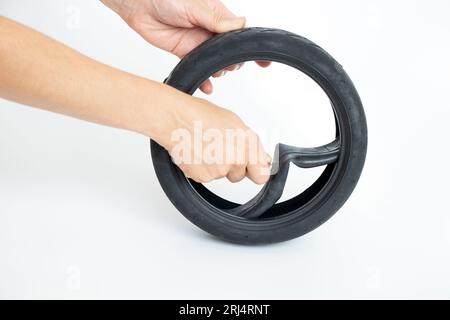 Reifen und Schlauch für einen Roller und die Hand einer Frau nimmt die Schläuche aus dem Reifen auf einem weißen Hintergrund, ändert die Röhre in einem Elektroroller, Repai Stockfoto