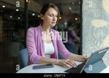 Porträt einer jungen, schönen Geschäftsfrau, die mit einem Laptop im Café sitzt. Fernarbeit in einem Café Stockfoto