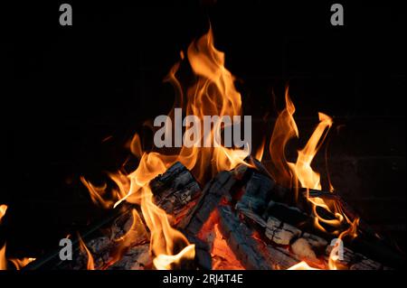 Holzstämme brennen im Kamin. Nahaufnahme. Flammenzungen auf dunklem Hintergrund. Stockfoto