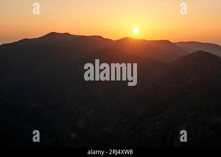Ein malerischer Blick auf den Sonnenuntergang hinter einer grünen Bergkette Stockfoto