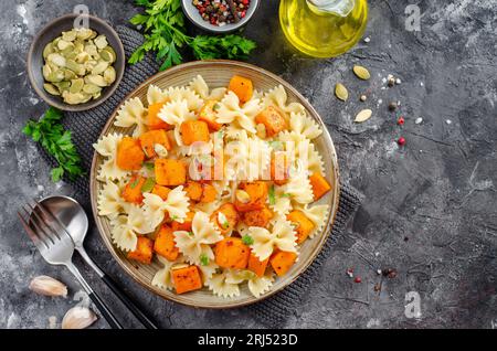 Pasta mit geröstetem Kürbis, Farfalle Pasta mit Kürbis auf einem Teller auf dunklem rustikalem Hintergrund Stockfoto