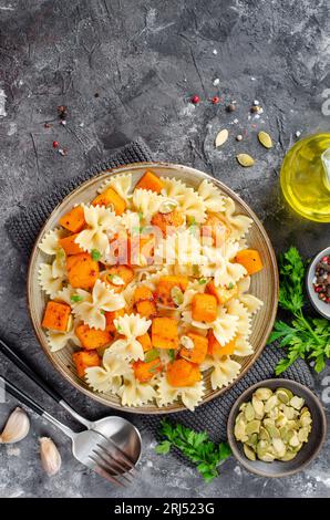 Pasta mit geröstetem Kürbis, Farfalle Pasta mit Kürbis auf einem Teller auf dunklem rustikalem Hintergrund Stockfoto
