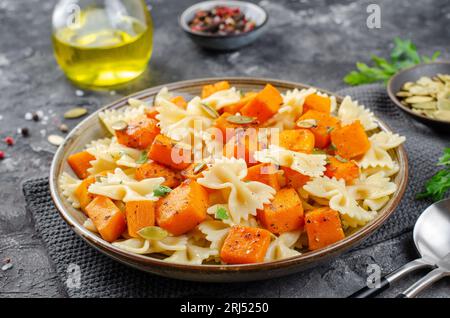 Pasta mit geröstetem Kürbis, Farfalle Pasta mit Kürbis auf einem Teller auf dunklem rustikalem Hintergrund Stockfoto