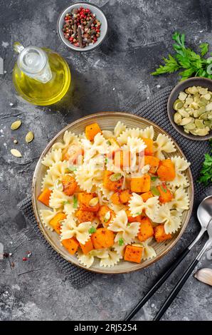 Pasta mit geröstetem Kürbis, Farfalle Pasta mit Kürbis auf einem Teller auf dunklem rustikalem Hintergrund Stockfoto