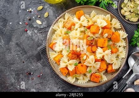 Pasta mit geröstetem Kürbis, Farfalle Pasta mit Kürbis auf einem Teller auf dunklem rustikalem Hintergrund Stockfoto