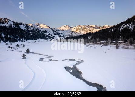 Eine ruhige Winterszene mit schneebedeckten Bäumen und einem Bach in der Ferne Stockfoto