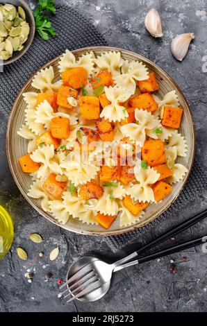 Pasta mit geröstetem Kürbis, Farfalle Pasta mit Kürbis auf einem Teller auf dunklem rustikalem Hintergrund Stockfoto