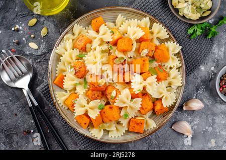 Pasta mit geröstetem Kürbis, Farfalle Pasta mit Kürbis auf einem Teller auf dunklem rustikalem Hintergrund Stockfoto