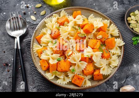 Pasta mit geröstetem Kürbis, Farfalle Pasta mit Kürbis auf einem Teller auf dunklem rustikalem Hintergrund Stockfoto
