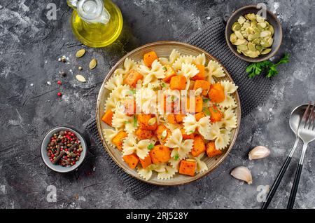 Pasta mit geröstetem Kürbis, Farfalle Pasta mit Kürbis auf einem Teller auf dunklem rustikalem Hintergrund Stockfoto