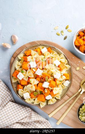 Pasta mit geröstetem Kürbis, Farfalle Pasta mit Kürbis und Feta-Käse auf einem Teller auf hellem Hintergrund Stockfoto