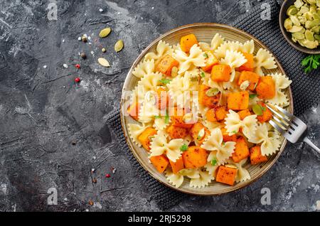 Pasta mit geröstetem Kürbis, Farfalle Pasta mit Kürbis auf einem Teller auf dunklem rustikalem Hintergrund Stockfoto