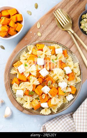 Pasta mit geröstetem Kürbis, Farfalle Pasta mit Kürbis und Feta-Käse auf einem Teller auf hellem Hintergrund Stockfoto