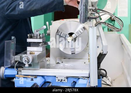 Ein männlicher Arbeiter arbeitet an einer größeren Metallschleusen-Drehmaschine, Ausrüstung für Reparaturen, Metallarbeiten in einer Werkstatt in einer Metallurgieanlage in einem Reparaturprogramm Stockfoto