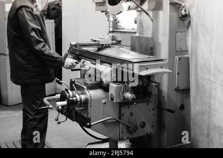 Ein männlicher Arbeiter arbeitet an einer größeren Metallschleusen-Drehmaschine, Ausrüstung für Reparaturen, Metallarbeiten in einer Werkstatt in einer Metallurgieanlage in einem Reparaturprogramm Stockfoto