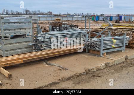 Viele Baumaterialien mit Metallersatzteilen, Stöcken, Balken, Rohren in einem Lagerhaus auf einer Baustelle im Freien. Stockfoto