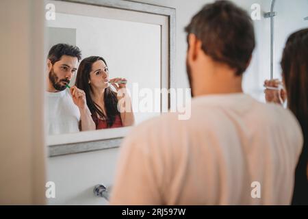 Ein junges Paar, das die Zähne im Badezimmer putzt Stockfoto