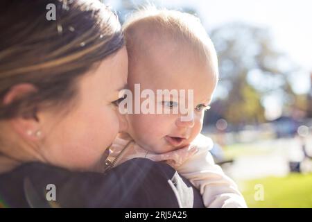 Nahaufnahme von Mutter, die ihre Tochter im Park hält. Stockfoto