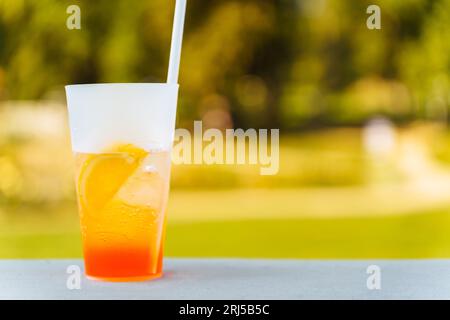Ein Glas mit einem Aperol Spritz Cocktail und ein Strohhalm im Sommer auf der Terrasse. Ein erfrischendes Sommergetränk. Stockfoto