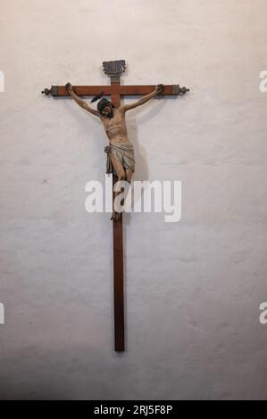 Eine vertikale Nahaufnahme von Jesus Christus nagelte sich an das hölzerne Kreuz, das an der Wand hing Stockfoto