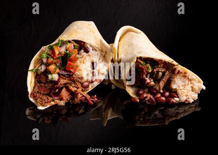 Zwei frisch zubereitete Burritos gefüllt mit schwarzen Bohnen und einer Auswahl an gehacktem Gemüse Stockfoto