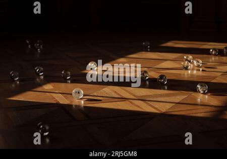 Eine Sammlung von Glaskugeln auf einem Holzboden, der von Sonnenlicht beleuchtet wird. Stockfoto