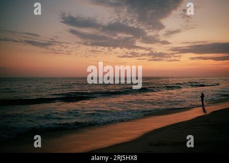 Eine Silhouetten-Person, die an einem Strand zur wunderschönen goldenen Stunde steht, Oaxaca Stockfoto