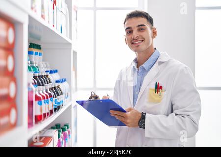Junger hispanischer Apotheker, der auf einem Dokument in der Apotheke schreibt Stockfoto