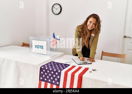 Junge schöne hispanische Frau Wahltisch Präsident schriftlich auf Zwischenablage an Wahlhochschule Stockfoto
