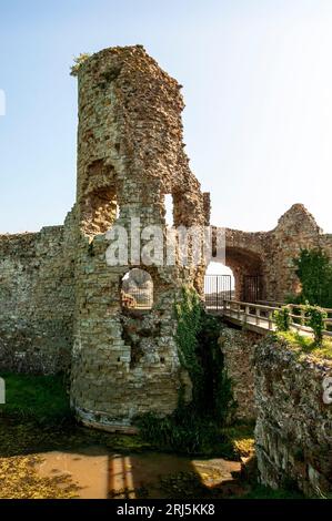 The ruins of Pevensey Castle gatehouse reached by crossing a wooden bridge over the moat Stock Photo