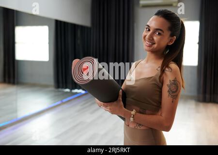 Porträt einer glücklichen jungen Frau mit Nasenpiercing und Yogamatte Stockfoto