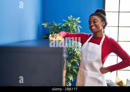 afroamerikanische Frau lächelt selbstbewusst Staub zu Hause zu putzen Stockfoto