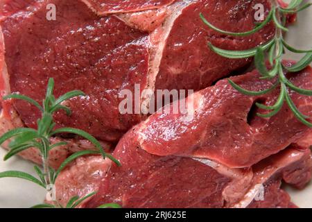 Rotes Fleisch, Draufsicht. Geschnittenes Steak dreht sich auf Holzbrett-Hintergrund. Flach liegend. Frisches rohes Fleisch mit Gewürzen und Kräutern. Black Angus Prime Meat St Stockfoto