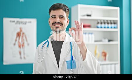 Junger hispanischer Arzt macht gute Geste in der Klinik Stockfoto