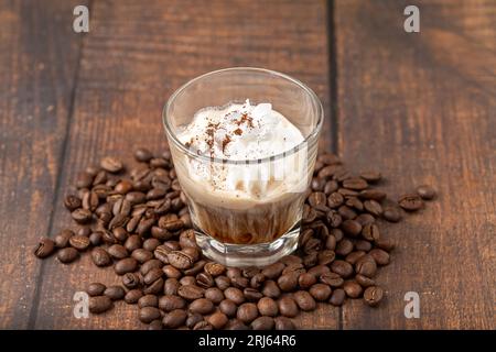 Heißer Espresso mit Panna in Glasbecher auf Holztisch Stockfoto