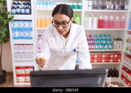 Junge arabische Apothekerin mit Computer-Pillen-Flasche in der Apotheke Stockfoto