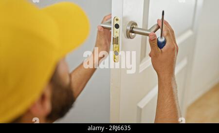 Junger hispano-Mann, der zu Hause eine Knopflose repariert Stockfoto