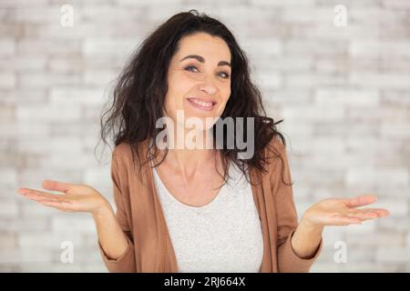Glückliche, reife Frau, die Gesten und Lächeln macht Stockfoto