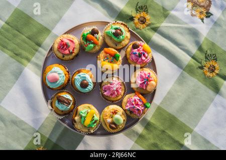 Eine Auswahl an bunten und köstlichen Cupcakes, kunstvoll auf einem weißen Teller in verschiedenen Formen angeordnet Stockfoto