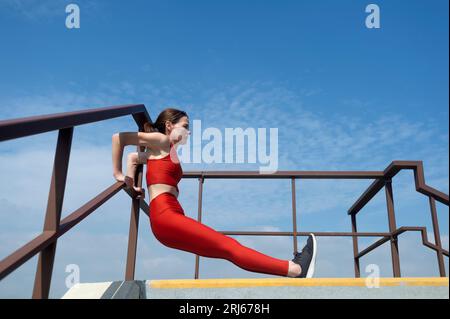 Seitenansicht der Frau in voller Länge, die sich rückwärts hochlegt. Outdoor-Fitnesskonzept. Stockfoto