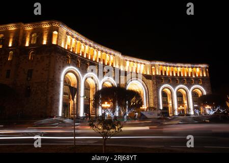 Beleuchteter Platz der Republik Armenien in einer kalten Winternacht mit langen Lichtspuren vorbeifahrender Autos, die den Vordergrund schmücken Stockfoto