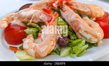 Große Garnelen mit Sauce auf Salatblättern und Tomaten, selektiver Fokus Stockfoto