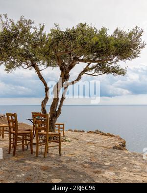 Ein Stühle im Freien am Rande eines ruhigen Sees, mit einem atemberaubenden Blick auf das Wasser in Monemvasia Castle Griechenland Stockfoto