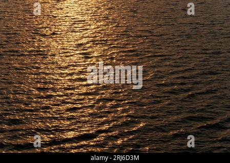 Ein wunderschöner, glänzender Sonnenuntergang auf einem wavey-Meer in einer Stadt, aus nächster Nähe Stockfoto