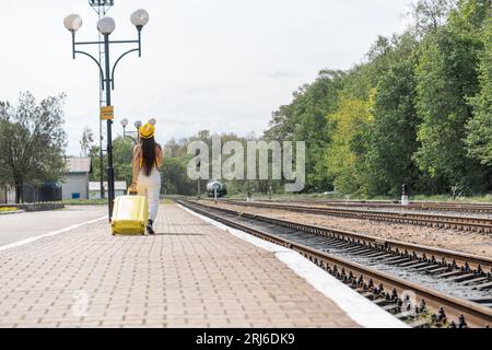 Raus in die Welt: Ein Mädchen mit stylischem Outfit und Brille fühlt sich von der bevorstehenden Reise begeistert. Eine junge Frau in gelber Kleidung und blau Stockfoto