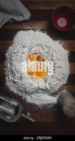 Die rohen Eier und das Mehl auf einem Holztisch Stockfoto