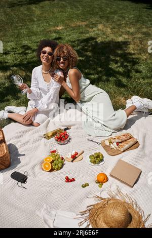 Sommerpicknick mit afroamerikanischen Freundinnen in der Nähe von frischem Obst und Gemüse im Park Stockfoto